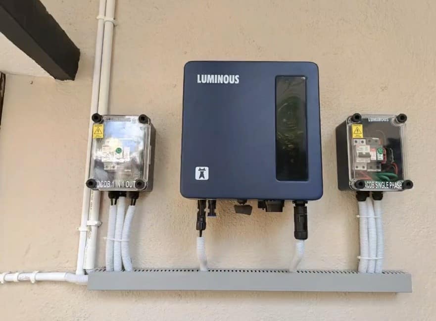 Wall-mounted string inverter with DCDB and ACDB boxes and labelled conduit runs at a completed Paso Solar installation